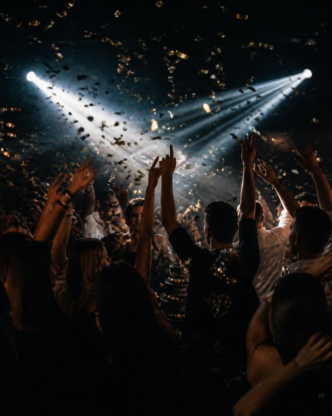 Guests dancing with hands raised under confetti at a private birthday party